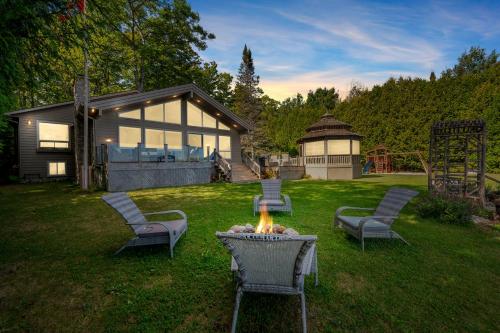 a backyard with a fire pit and chairs and a house at Grotto Escape Unwind At Cameron Lakehouse in Tobermory