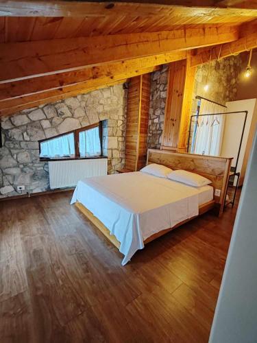 a bedroom with a bed and a stone wall at Vila Nikol in Voskopojë