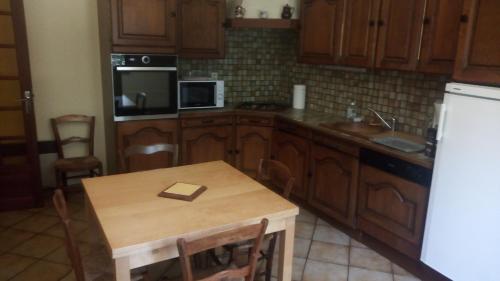 a kitchen with a table and a white refrigerator at Les Mimosas in Brens