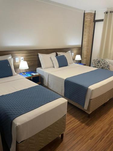 a hotel room with two beds and two lamps at Bliss Hotel Vale do Café in Vassouras