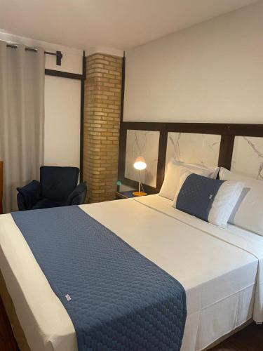 a bedroom with a large bed and a chair at Bliss Hotel Vale do Café in Vassouras