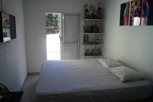 a bedroom with a bed in a room with a window at Casa super confortável para você e sua família, próximo a praia in Guarujá