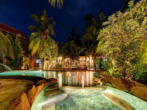 a swimming pool in a resort at night at Ganesh Lodge in Candidasa