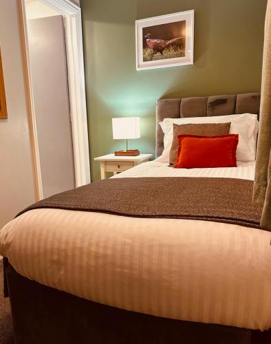 a bedroom with a large bed with a red pillow at The Old Pheasant in Glaston