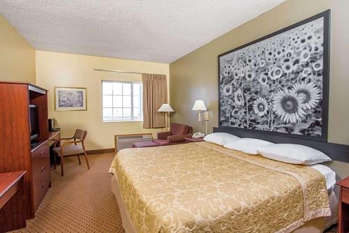 a hotel room with a bed and a large painting on the wall at Western Inn & Suites in Osage