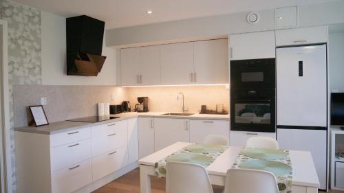 a kitchen with white cabinets and a table and chairs at Rådjursstigen 2A Vimmerby in Vimmerby
