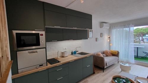 une cuisine avec des placards verts et un salon dans l'établissement Appartement cosy en centre-ville de Royan à 200m plage, à Royan