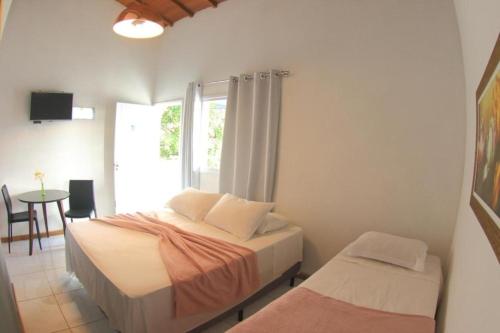 a bedroom with two beds and a table and a window at Pousada JMedina Maresias in Maresias