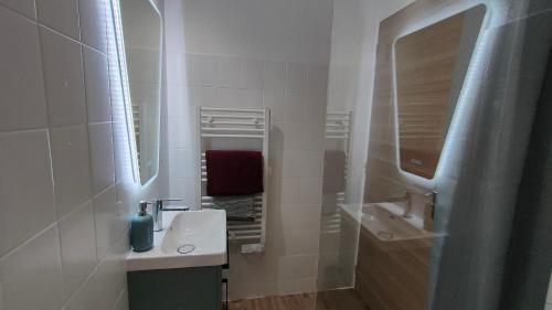 a white bathroom with a sink and a mirror at Appartement cosy en centre-ville de Royan à 200m plage in Royan