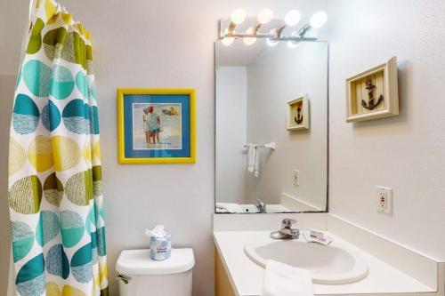 a bathroom with a sink and a toilet and a mirror at Dream Chaser-Private Pool-Pet Friendly-Directly across from boardwalk to beach in St. George Island