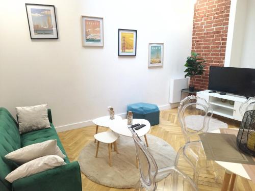 ein Wohnzimmer mit einer grünen Couch und einem Tisch in der Unterkunft Spacieux appartement proche de Paris Stade de France Métro in Aubervilliers