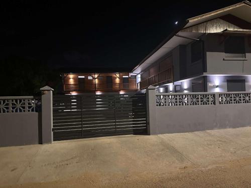a house with a gate at night with lights at T1 avec piscine a 50 metre de la mer in Cayenne