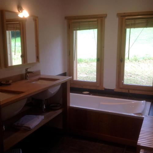 La salle de bains est pourvue d'une baignoire, d'un lavabo et de 2 fenêtres. dans l'établissement chalet classé 4 étoiles face aux Aravis plein sud 12 personnes, au Grand-Bornand