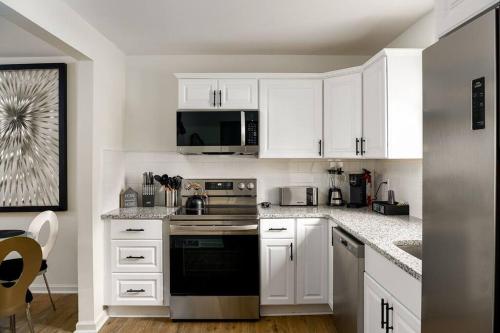a kitchen with white cabinets and a stove top oven at Grey Sapphire Hideaway - 2BR 2BA w Arcade & Pool in Winston-Salem