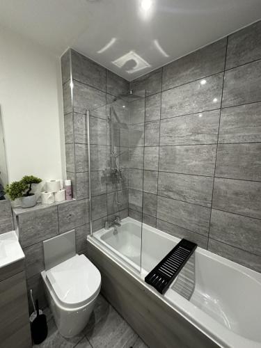 a bathroom with a toilet and a tub and a sink at Luxe Apartment - Leicester City Centre in Leicester