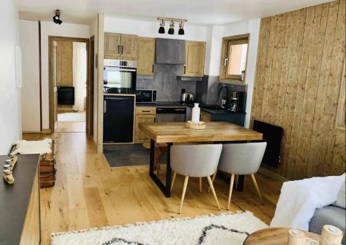 une cuisine avec une table en bois et quelques chaises dans l'établissement Magnifique appartement au coeur de Megève, à Megève