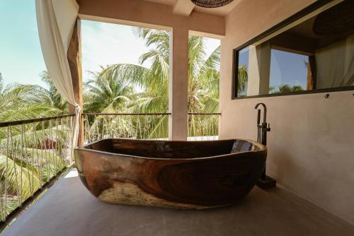 una gran bañera de madera en un baño con ventana en Nikau Hotel El Cuyo - Adults Only, en El Cuyo
