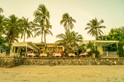 a restaurant on the beach with palm trees in the background at Green Gallery Beach Boutique Hotel in Hua Hin