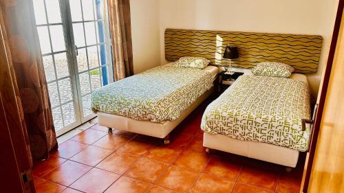 a bedroom with two beds and a window at Charmoso Apartamento T2 em Foros de Salvaterra in Monte de Lucas