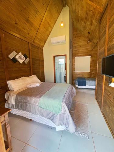 a bedroom with a bed in a room with wooden walls at Pousada Canastra Sul in Delfinópolis