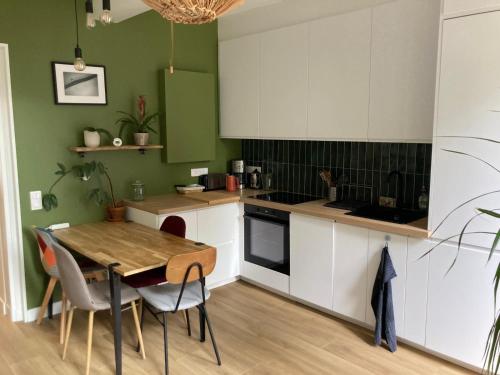 une cuisine avec des armoires blanches et une table avec des chaises dans l'établissement Joli appartement avec jardin-Parc de la Villette, à Le Pré-Saint-Gervais