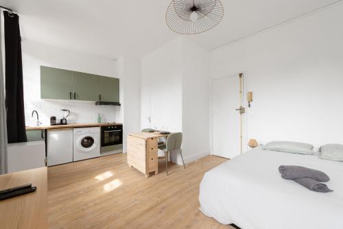 une chambre blanche avec un lit et une cuisine dans l'établissement Le verdoyant - studio au coeur de Toulouse, à Toulouse