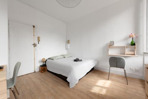 une chambre blanche avec un lit et une chaise dans l'établissement Le verdoyant - studio au coeur de Toulouse, à Toulouse