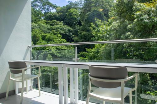 two chairs on a balcony with a view of trees at Punta Esmeralda by Punta Leona in Jacó