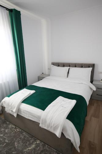a bedroom with a large bed with white and green sheets at Camere de inchiriat Adyden in Arbore