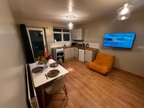 a living room with a table and a kitchen at Glenside Farm Apartment in Bryansford