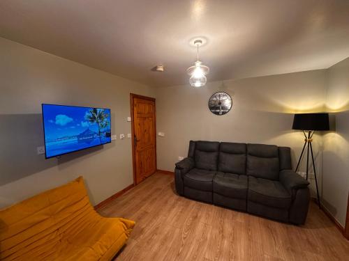 a living room with a couch and a flat screen tv at Glenside Farm Apartment in Bryansford