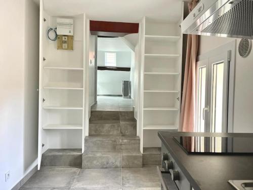 un couloir avec des étagères blanches et un escalier dans l'établissement Apt 5 Dammartin, à Dammartin-en-Goële