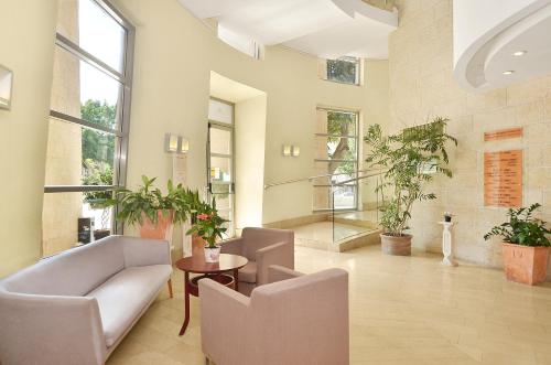a living room with chairs and a table and windows at Ruth Daniel Residence in Tel Aviv