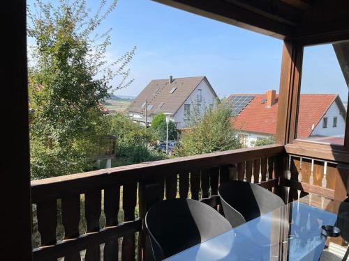 a table and chairs on a balcony with a view at Appartio - Ferienwohnung "Dorfblick" Dachgeschoss - 6 Personen - Netflix - Waschmaschine in Hofheim in Unterfranken