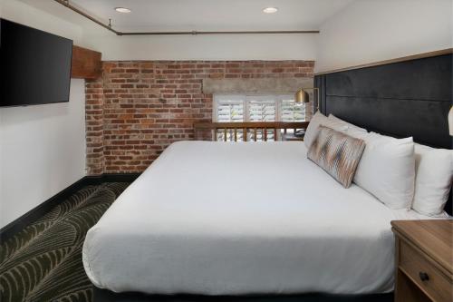 a bedroom with a large bed and a brick wall at The Ansonborough in Charleston