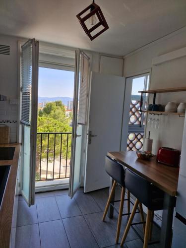 une cuisine avec une table et une vue sur un balcon dans l'établissement Escapade Montesquieu, à Perpignan