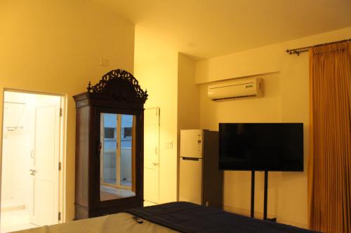 a bedroom with a bed and a mirror and a television at Terrace Suite in Champa Villa in Gandhinagar