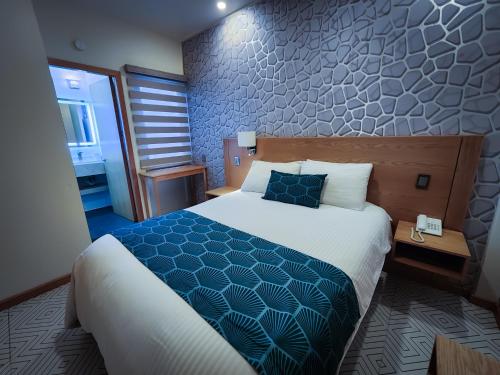 a hotel room with a bed with a blue and white comforter at HOTEL AZUL AGAVE in Arandas