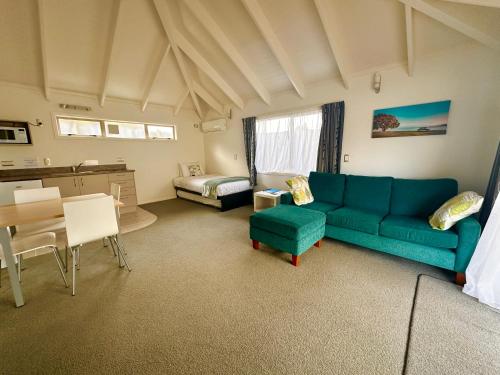 a living room with a blue couch and a table at The Olive Motel in Coromandel Town