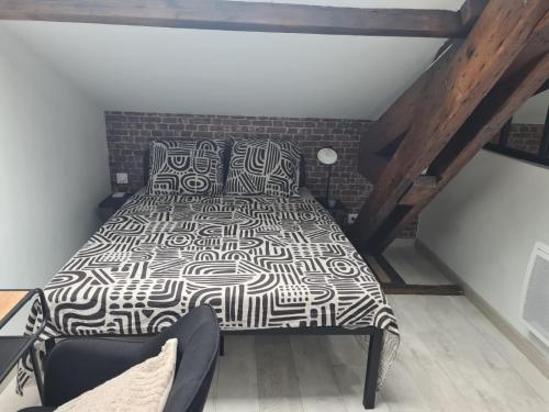 - une chambre avec un lit noir et blanc et un mur en briques dans l'établissement Charmant mini loft atypique proche paris 13, à Ivry-sur-Seine