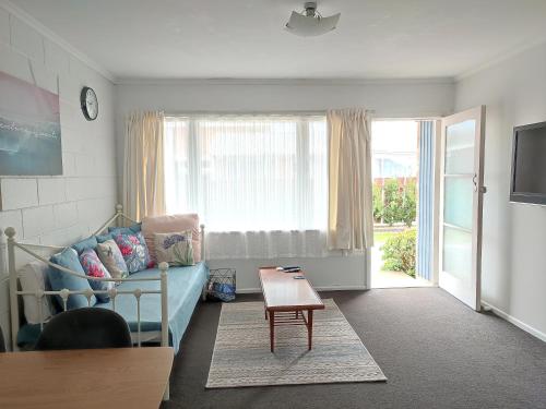 a living room with a blue couch and a table at Nesting In Hamilton East in Hamilton