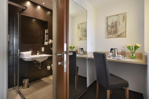 a bathroom with a sink and a desk with a chair at Prague Season Hotel in Prague
