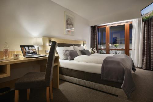 a bedroom with a bed and a desk with a laptop at Prague Season Hotel in Prague