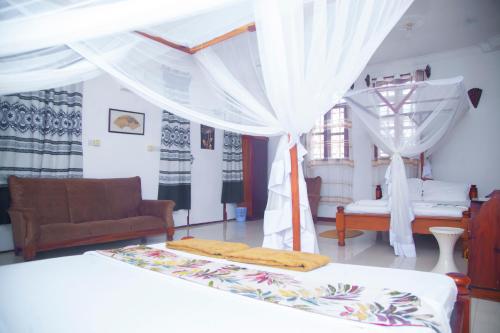 a bedroom with a bed and a couch and curtains at SULKHAN SERVICED APARTMENT in Chukwani