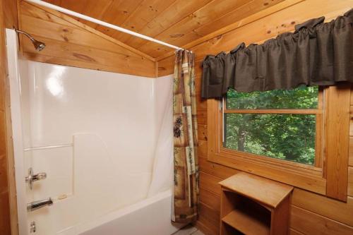a bathroom with a window and a tub and a shower at Thunder Bear Hideaway Roar Into Relaxation in Pigeon Forge