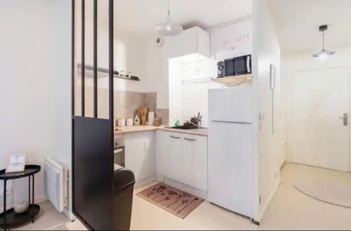 une cuisine avec des armoires blanches et un réfrigérateur noir dans l'établissement Paris à quelques pas, à Pierrefitte-sur-Seine