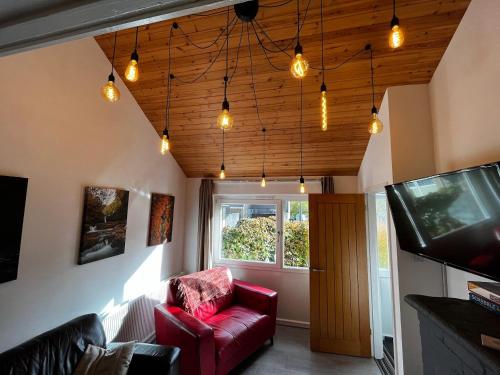 a living room with a red chair and a television at Waterfall Lodge in Pont-Nedd-Fechan