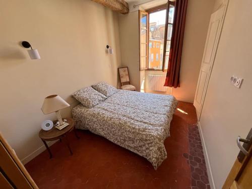 a small bedroom with a bed and a window at Place aux Aires in Grasse