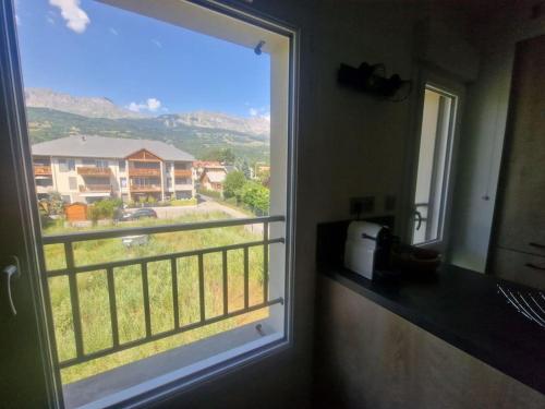 a window in a bathroom with a view of a house at Superbe T2 duplex vue sur les montagnes in Chorges