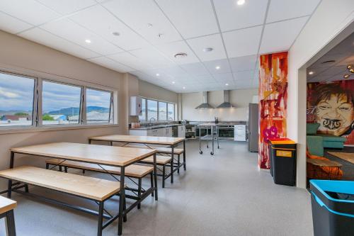a cafeteria with tables and chairs and windows at Rock Solid Backpackers Rotorua in Rotorua